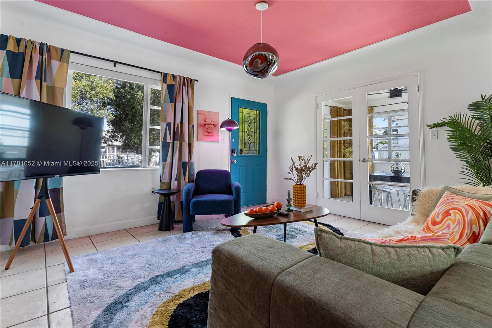 A living room features a bright pink ceiling, a blue front door, and patterned curtains — 260 NE 45th St, Miami FL 33137, MIAMI, FL
