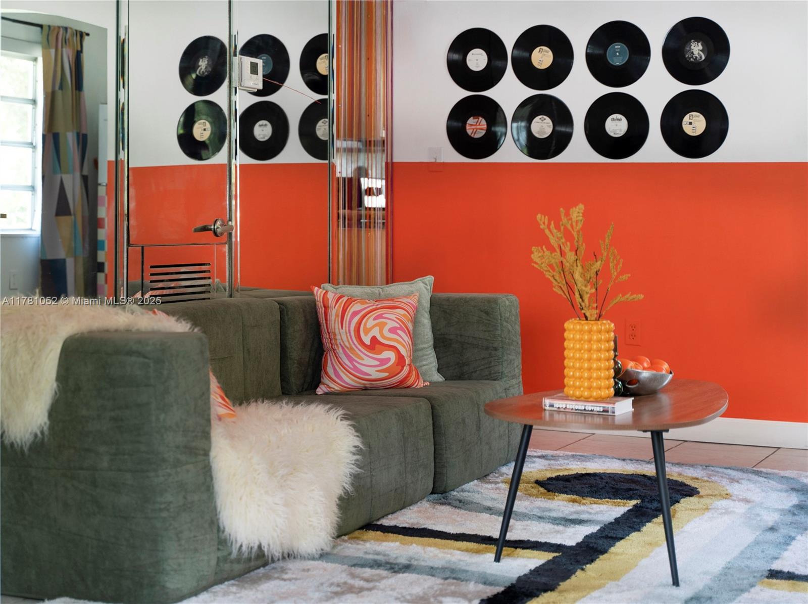 A living room features a green sofa, orange wall paint, and vinyl records on the wall — 260 NE 45th St, Miami FL 33137, MIAMI, FL