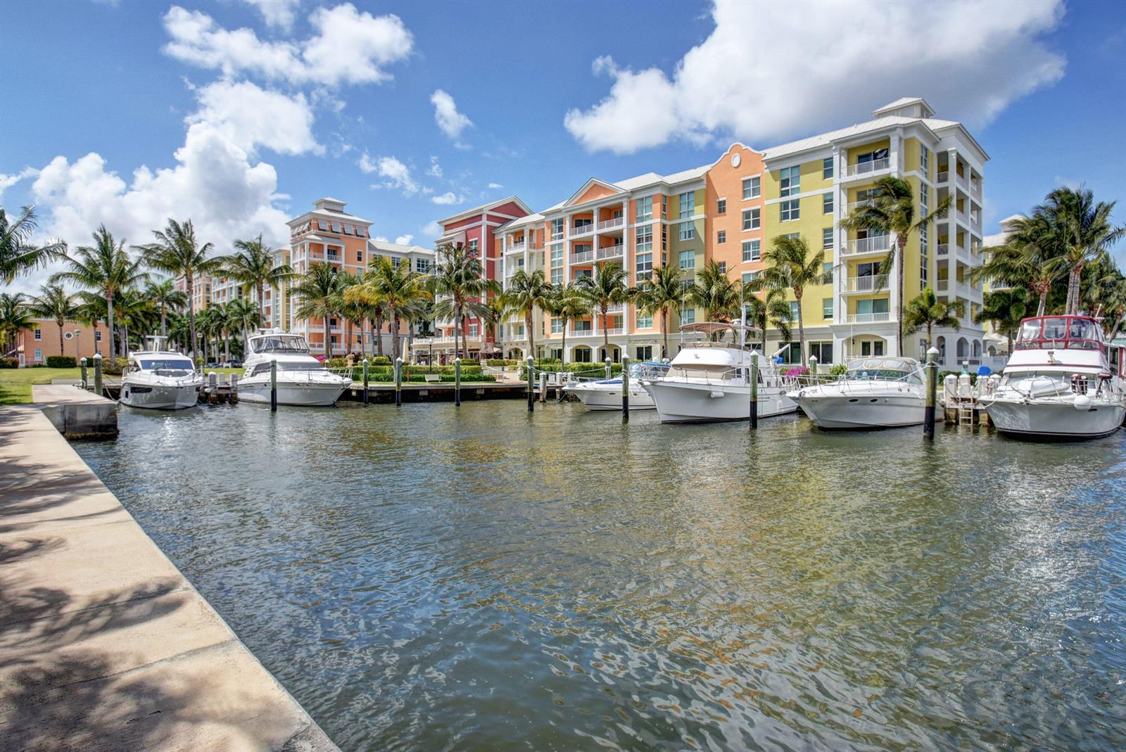 A row of colorful multi-story buildings sits along a canal with several docked motor yachts — 802 W Windward Way # 304, Lantana FL 33462, LANTANA, FL