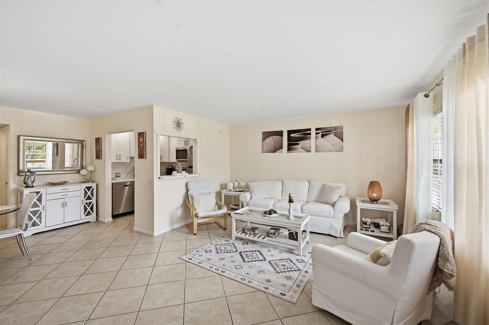 A living room with tile floors, a white sofa, and an open pass-through to the kitchen — 314 Brighton # H, Boca Raton FL 33434, BOCA RATON, FL