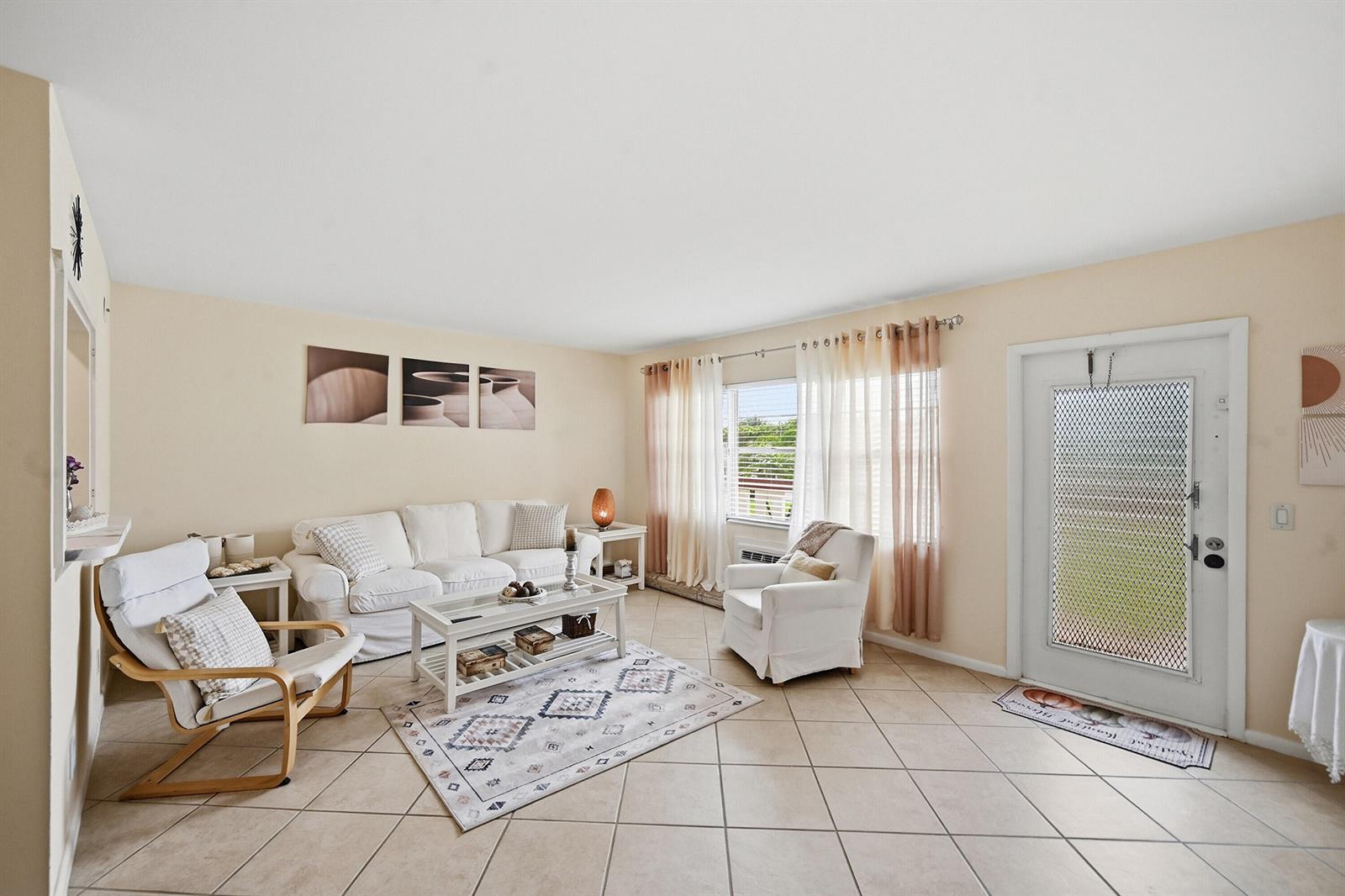 A living room features tile flooring, white furniture, a patterned area rug, and a front door — 314 Brighton # H, Boca Raton FL 33434, BOCA RATON, FL