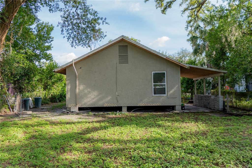 The exterior of a house with a stucco finish, a gable roof, and a covered patio — 1906 E CARACAS STREET, TAMPA, FL