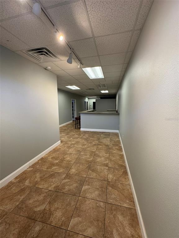 An interior view of a commercial space with tiled floors, gray walls, and drop ceilings — 2401 W BAY DRIVE UNIT 601, LARGO, FL