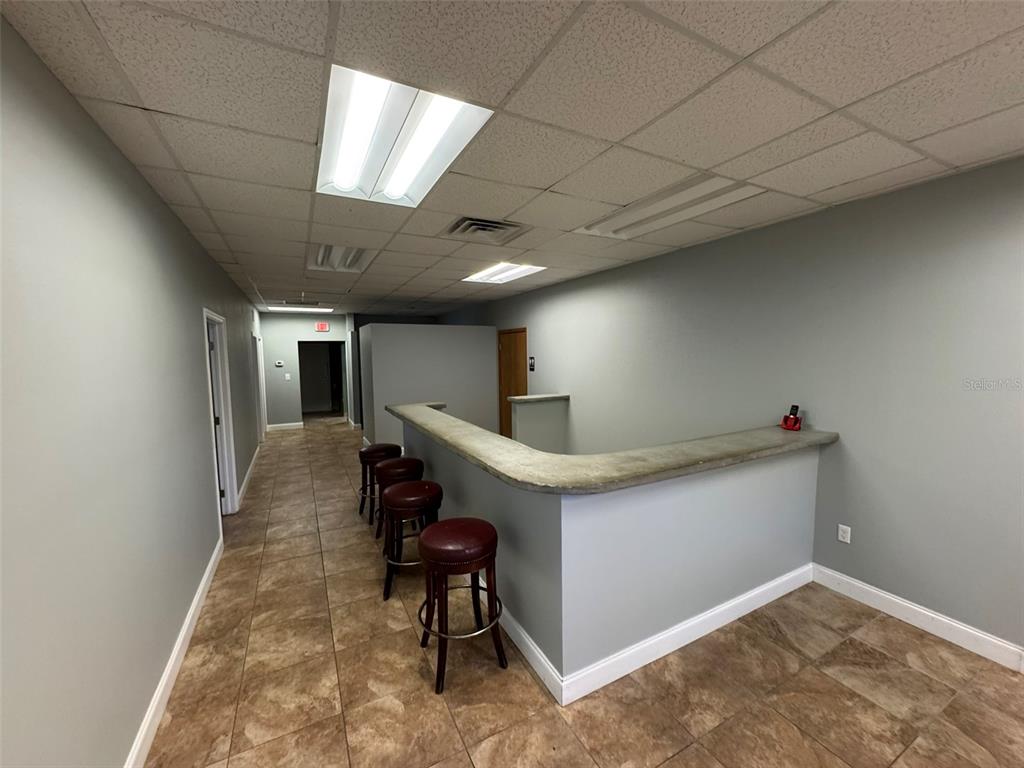 An interior view of a commercial space featuring a reception counter, barstools, and tiled flooring — 2401 W BAY DRIVE UNIT 601, LARGO, FL