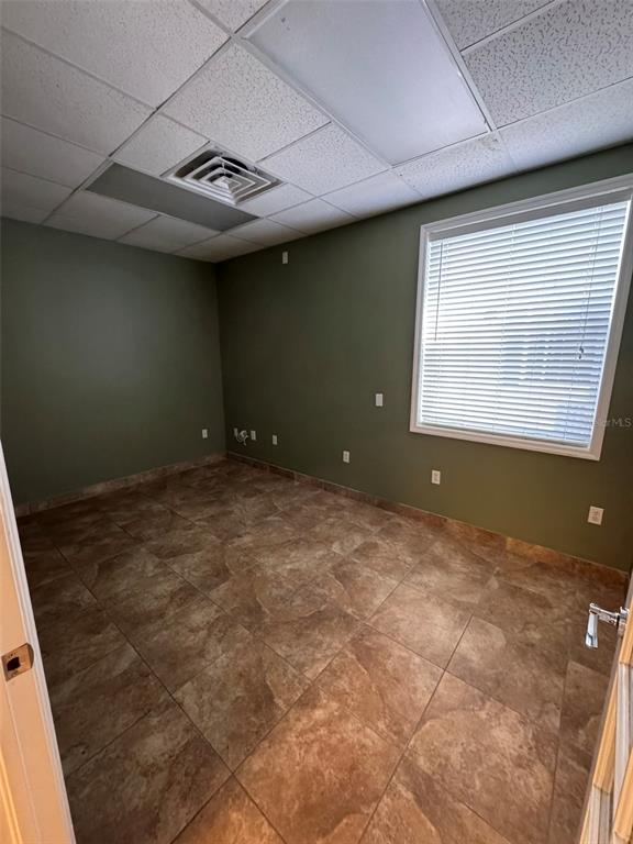 An empty office room features olive green walls, tiled flooring, and a window with blinds — 2401 W BAY DRIVE UNIT 601, LARGO, FL