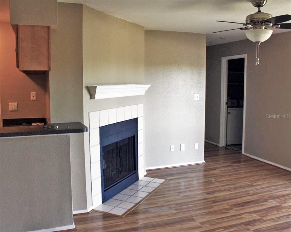 A living room features a fireplace with white tile, a wood-look floor, and a ceiling fan — 9100 DR MARTIN LUTHER KING JR STREET N UNIT 906, ST PETERSBURG, FL