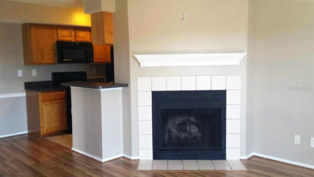 A living room features a fireplace with a white mantel and a nearby kitchen area — 9100 DR MARTIN LUTHER KING JR STREET N UNIT 906, ST PETERSBURG, FL