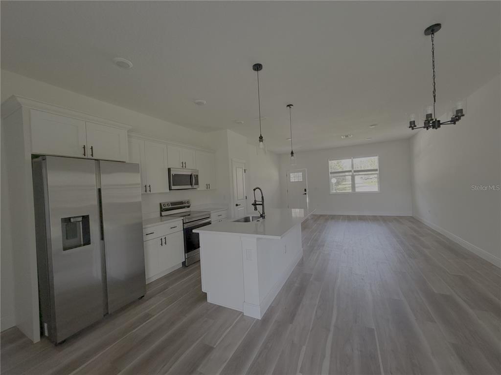 A modern kitchen features white cabinetry, stainless steel appliances, and a central island with seating — 1852 W QUAKER LANE, CITRUS SPRINGS, FL