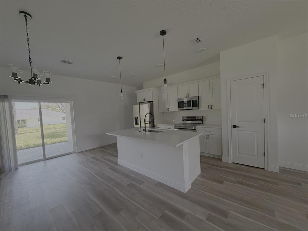 A kitchen with white cabinets, a central island, and light wood-look flooring — 1852 W QUAKER LANE, CITRUS SPRINGS, FL