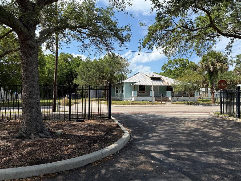 A light blue house with a metal roof sits behind a black metal fence — 585 WASHINGTON STREET, NEW SMYRNA BEACH, FL