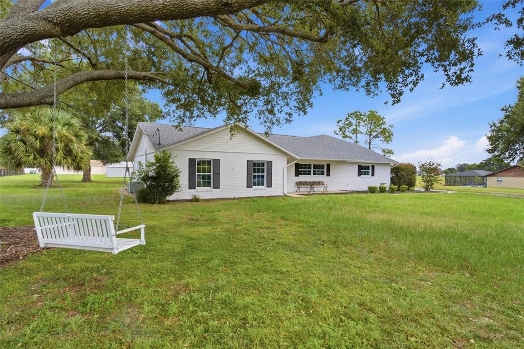 A white, single-story house with a large yard and a hanging bench under a tree — 5101 LAKE GRIFFIN ROAD, LADY LAKE, FL