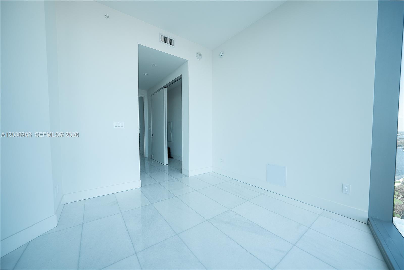 A bright, empty room features white tile flooring, white walls, and a large floor-to-ceiling window — 175 SE 25th Rd # 2703, Miami FL 33129, MIAMI, FL