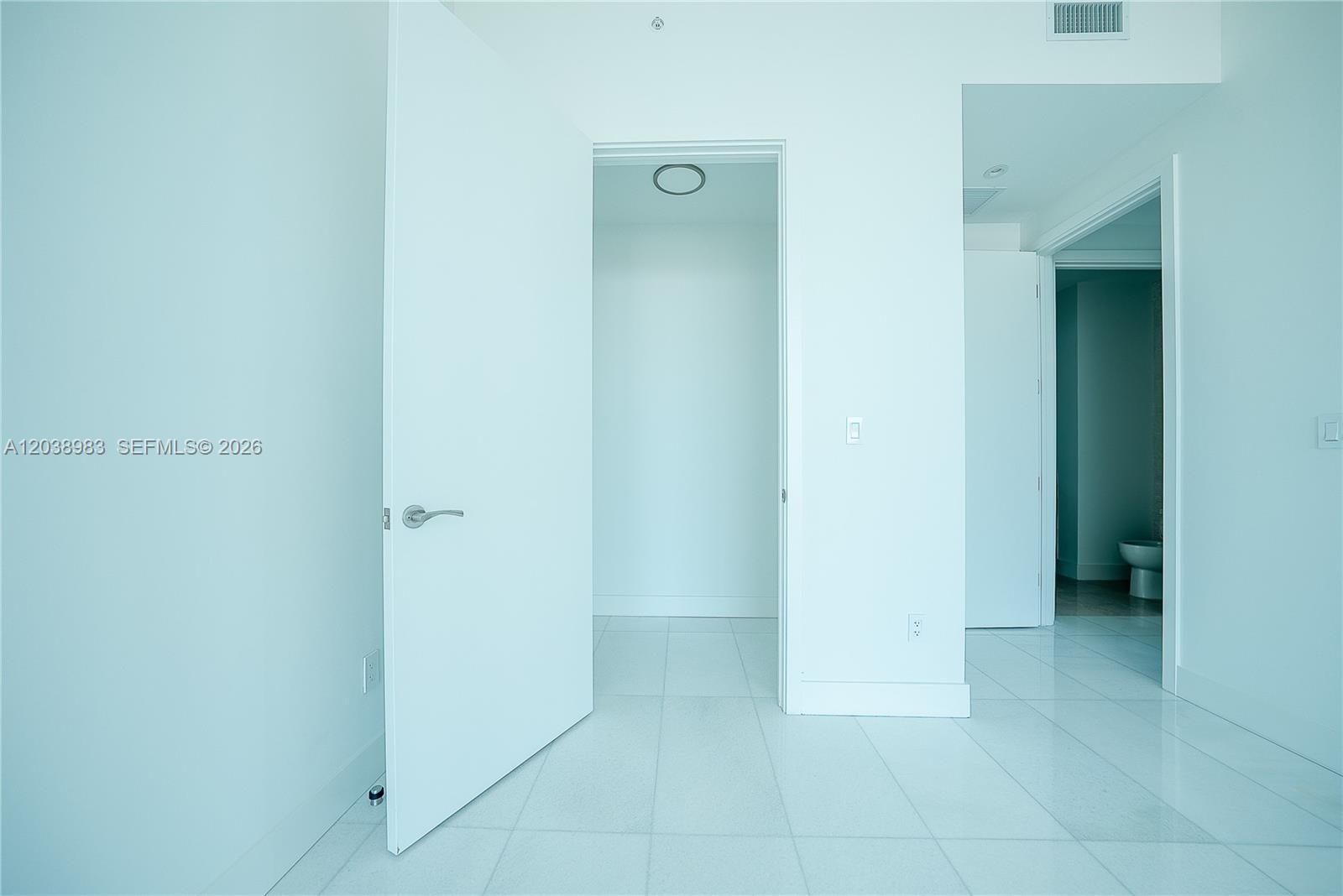 A white-walled room features tiled flooring, an open doorway to a closet, and a bathroom — 175 SE 25th Rd # 2703, Miami FL 33129, MIAMI, FL