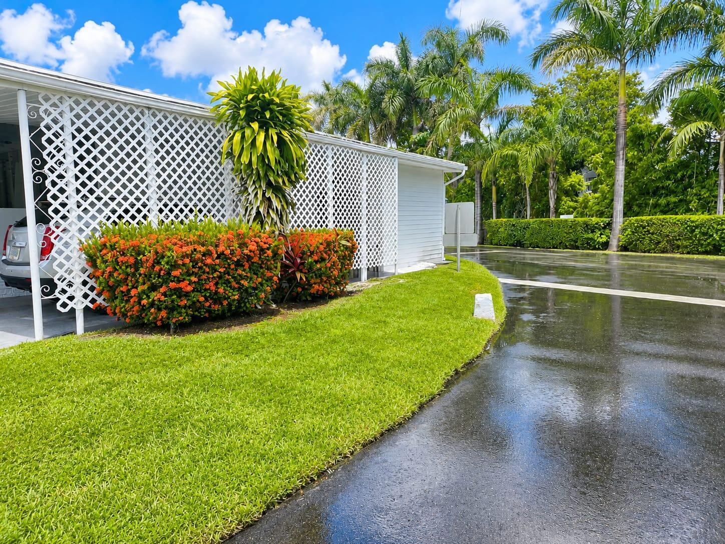 A white building with lattice siding sits beside a wet driveway and a green lawn — 3302 Lake Street, Hollywood FL 33021, HOLLYWOOD, FL
