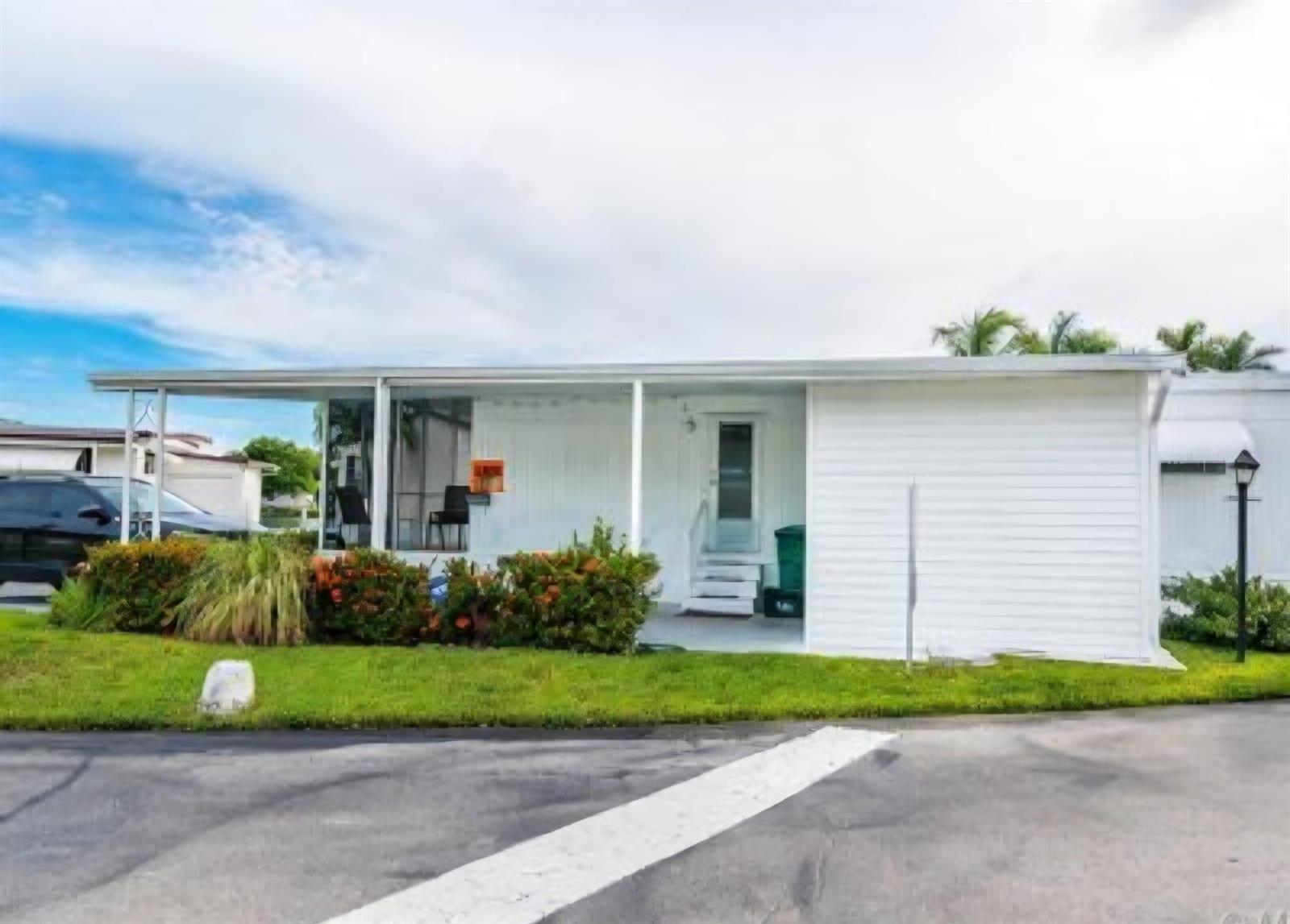 A white mobile home features a covered porch, a small front lawn, and a driveway — 3302 Lake Street, Hollywood FL 33021, HOLLYWOOD, FL