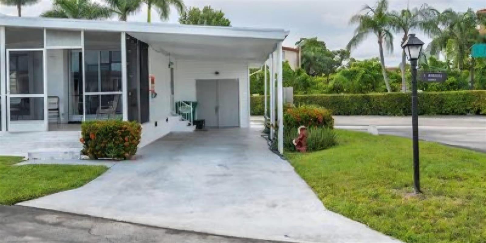 A white mobile home features a concrete carport, a screened porch, and a front lawn — 3302 Lake Street, Hollywood FL 33021, HOLLYWOOD, FL