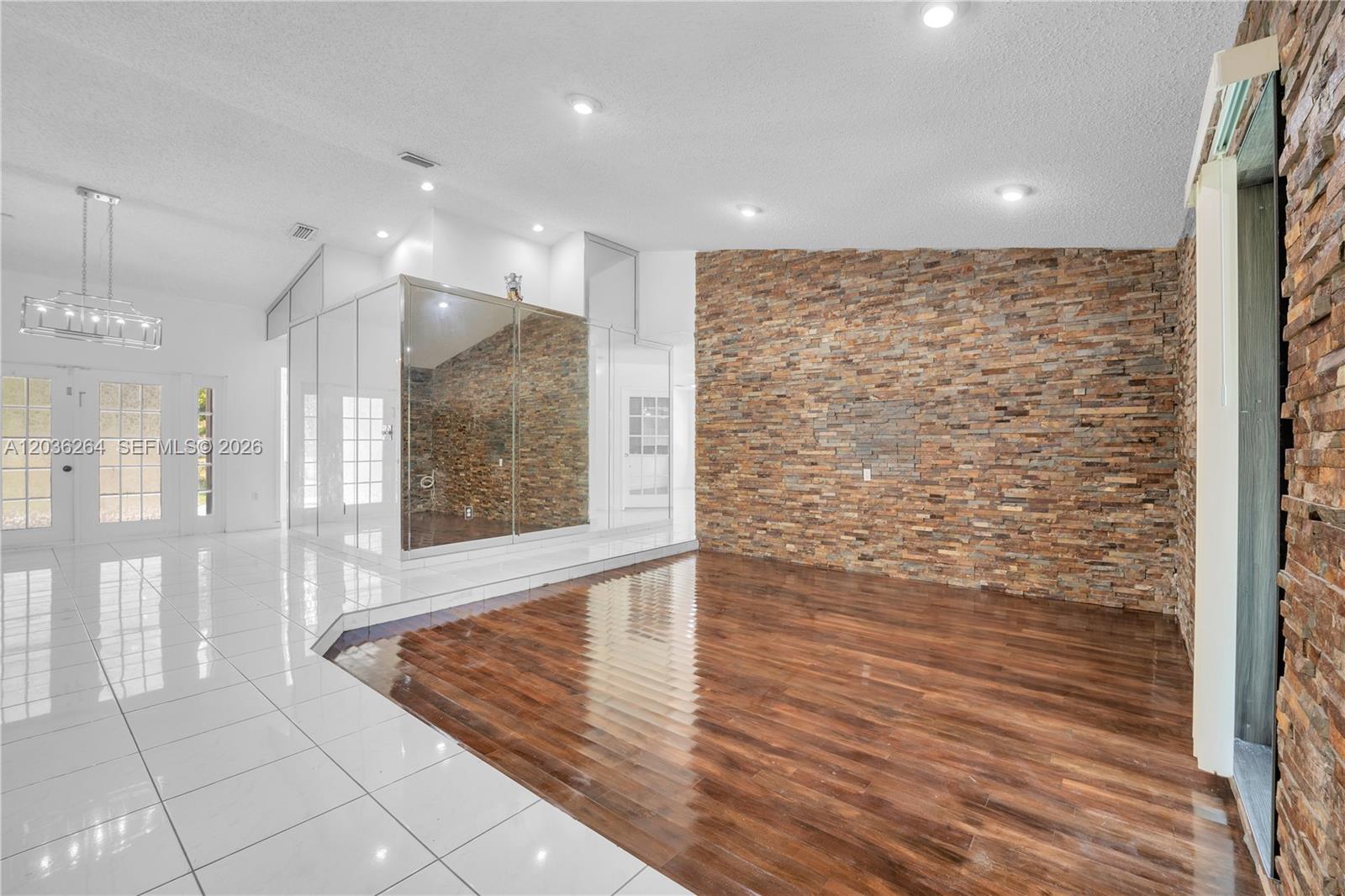 A room features a stone accent wall, dark wood flooring, and a mirrored wall section — 15241 SW 150th St, Miami FL 33196, MIAMI, FL