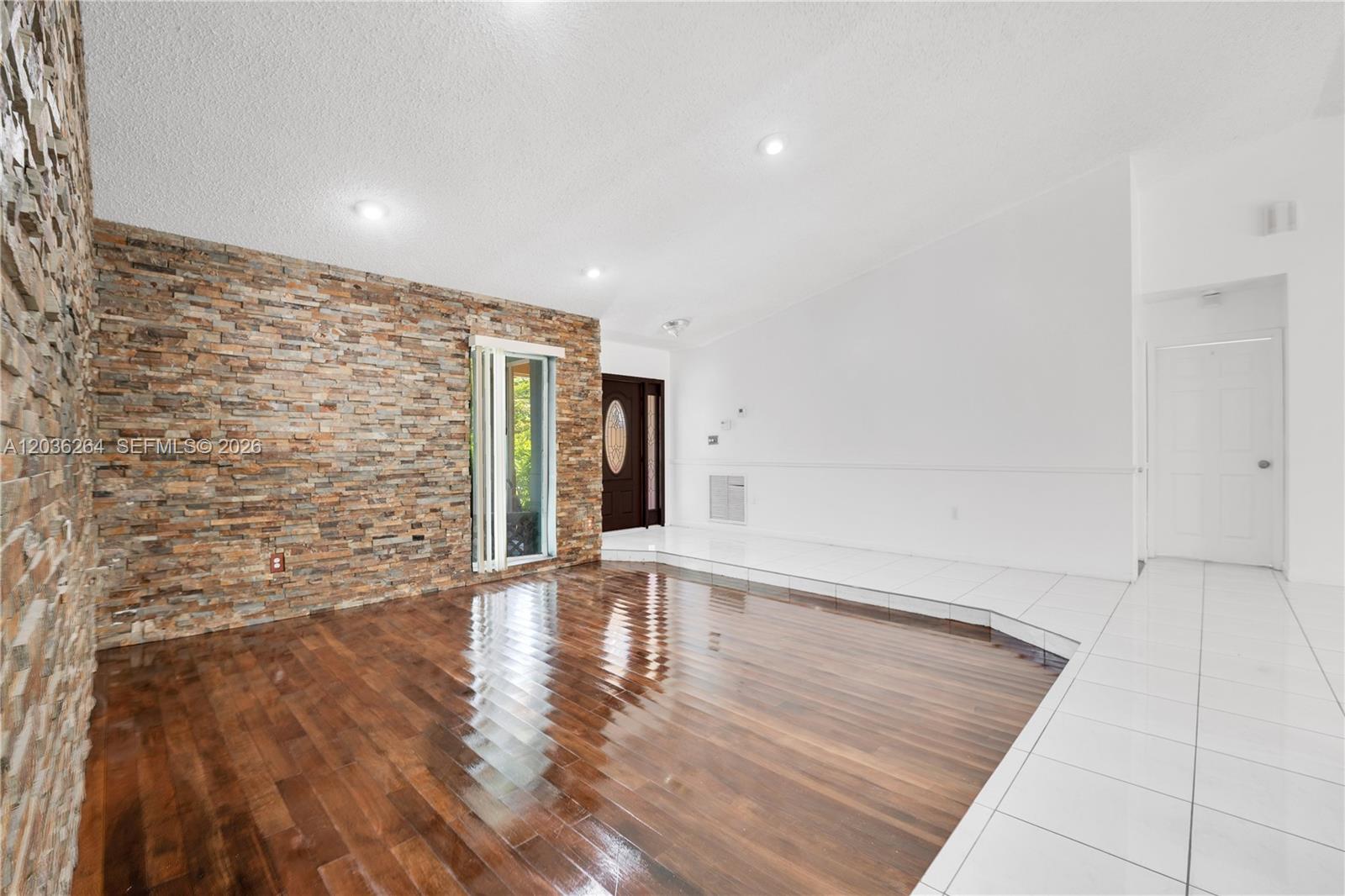 A living room features a stone accent wall, dark hardwood floors, and white tile flooring — 15241 SW 150th St, Miami FL 33196, MIAMI, FL