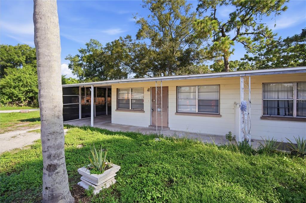 A single-story house with a covered porch, light siding, and a grassy front yard — 5801 11TH STREET COURT E, BRADENTON, FL
