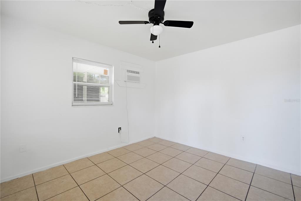 An empty room with white walls, tiled flooring, a ceiling fan, and a window unit — 5801 11TH STREET COURT E, BRADENTON, FL