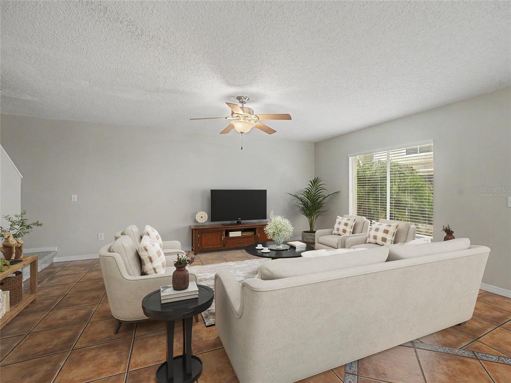 A living room features light-colored sofas, a television on a wooden console, and tile flooring — 12917 JESSUP WATCH PLACE, RIVERVIEW, FL