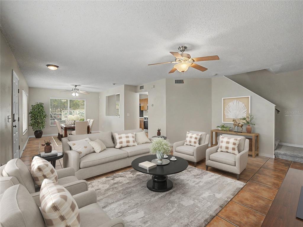 A living room with tile floors, a ceiling fan, and neutral furniture opens to a dining area — 12917 JESSUP WATCH PLACE, RIVERVIEW, FL
