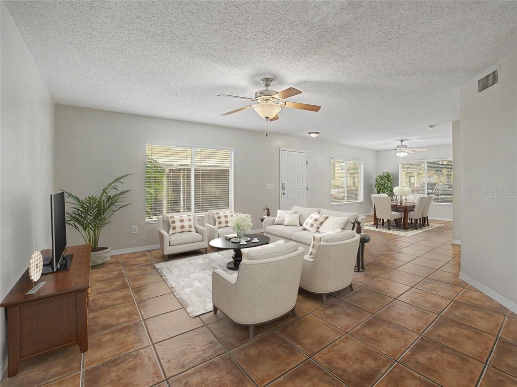 A living room with tile floors, a ceiling fan, and an adjacent dining area — 12917 JESSUP WATCH PLACE, RIVERVIEW, FL