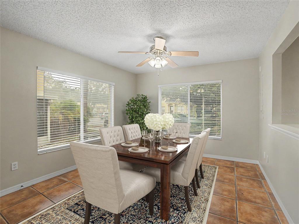 A dining room features a wooden table with six chairs, tile flooring, and two windows — 12917 JESSUP WATCH PLACE, RIVERVIEW, FL