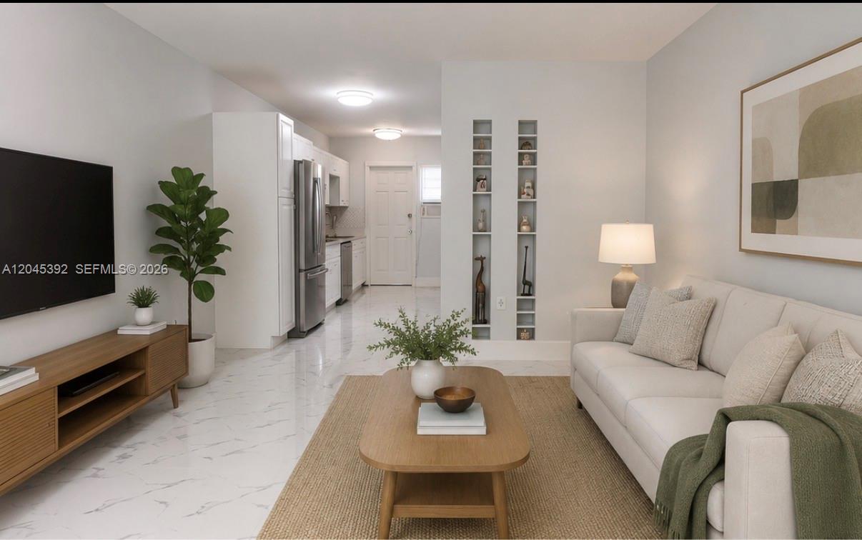 A living room with a sofa, coffee table, and television, open to a white kitchen — 636 Meridian Ave # 4, Miami Beach FL 33139, MIAMI BEACH, FL
