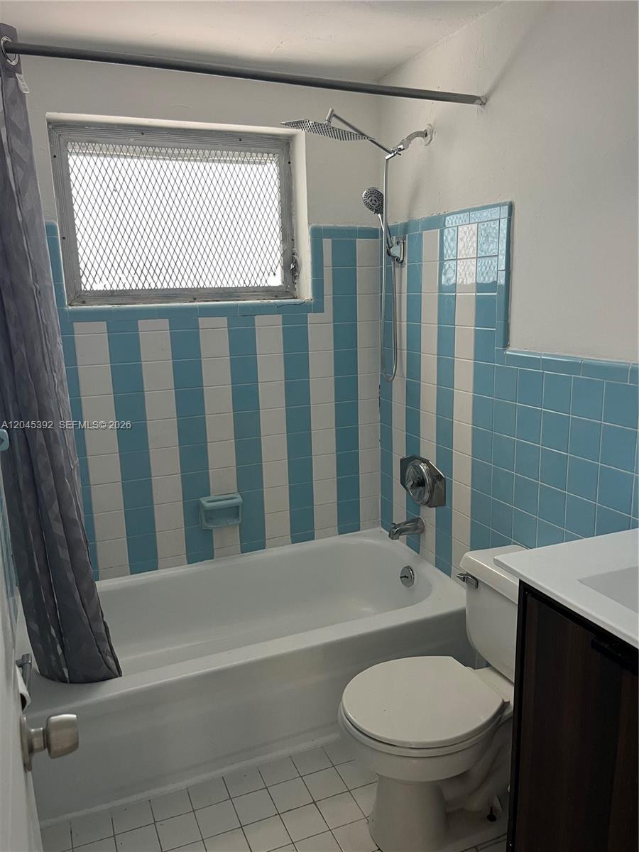 A bathroom features a bathtub with blue and white striped wall tiles and a window — 636 Meridian Ave # 4, Miami Beach FL 33139, MIAMI BEACH, FL
