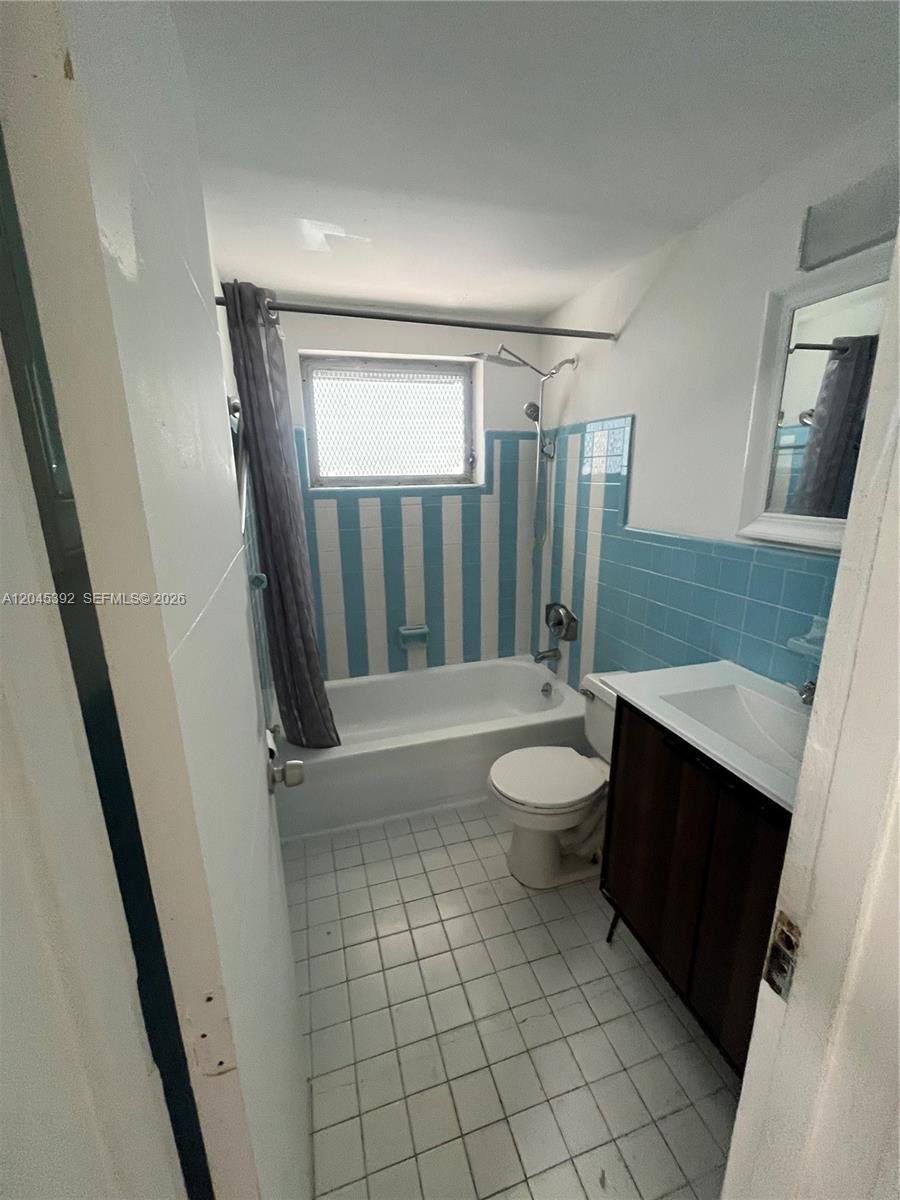 A small bathroom features a bathtub with blue and white striped tile walls — 636 Meridian Ave # 4, Miami Beach FL 33139, MIAMI BEACH, FL