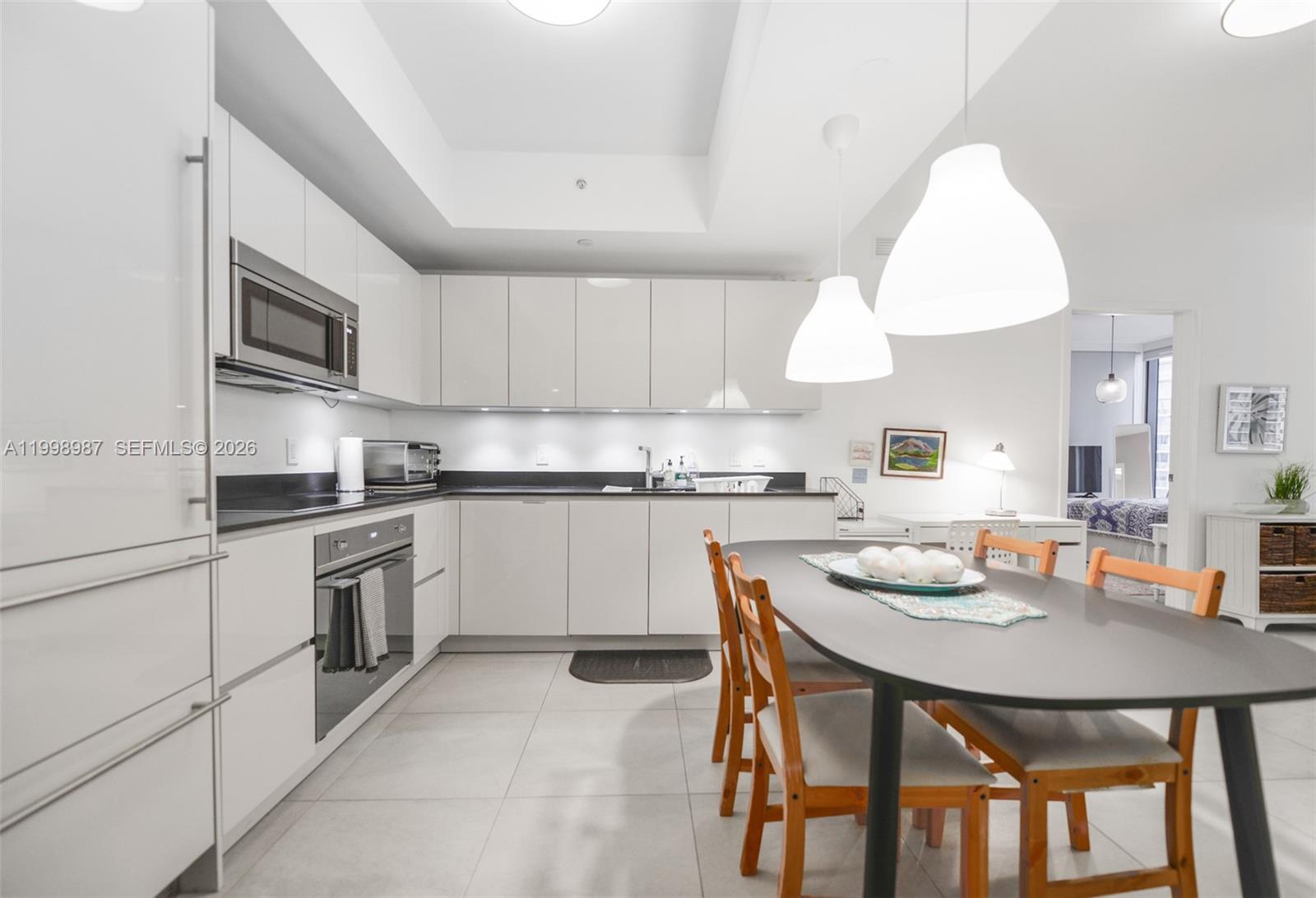 A modern kitchen features white cabinetry, stainless steel appliances, and a dining table with chairs — 1010 Brickell Ave # 2906, Miami FL 33131, MIAMI, FL