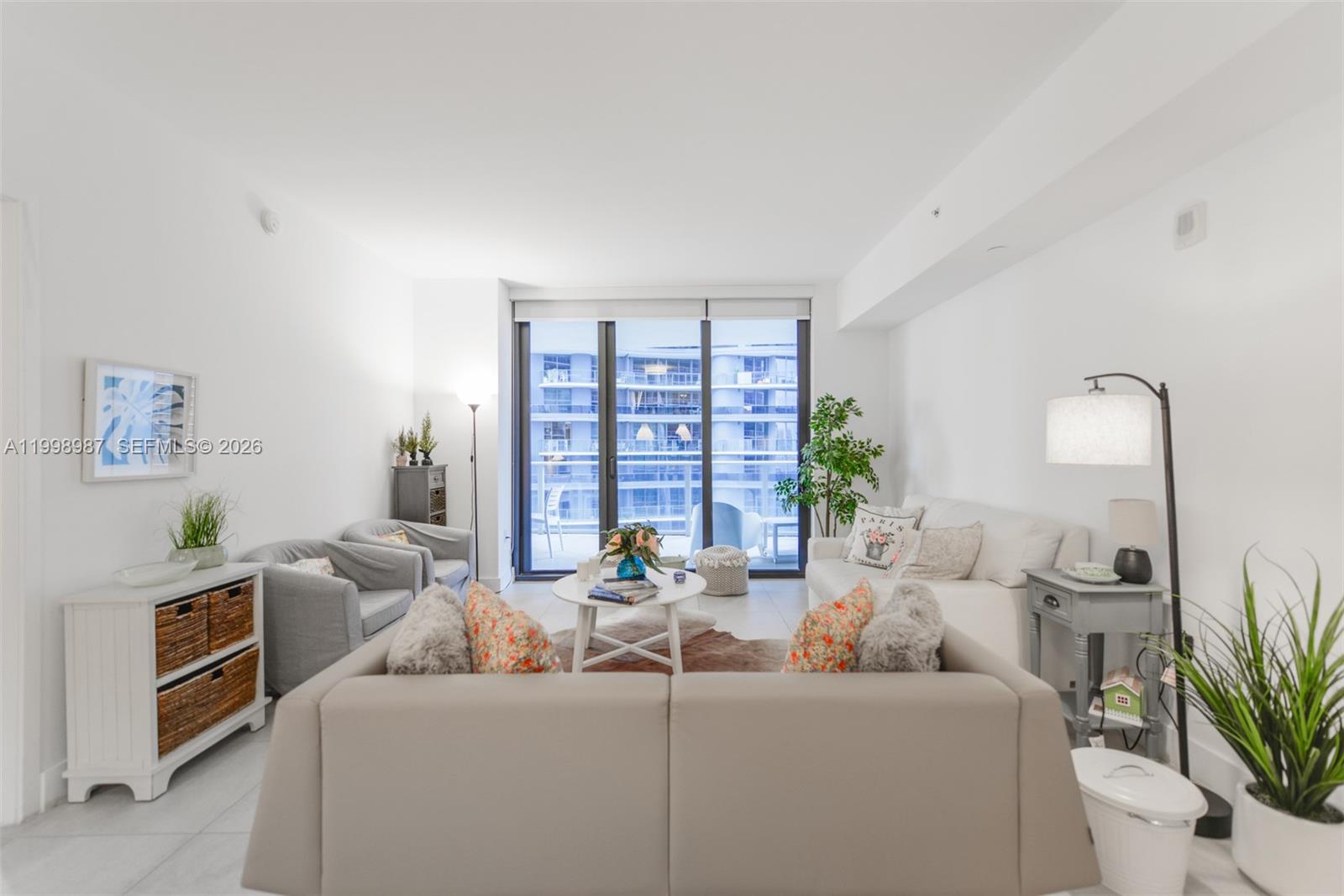 A bright living room features a white sofa, grey armchairs, and a balcony view — 1010 Brickell Ave # 2906, Miami FL 33131, MIAMI, FL