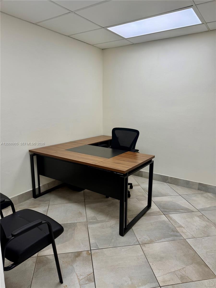 A small office features a wooden L-shaped desk, a black chair, and tiled flooring — 150 Westward Dr # 1, Miami Springs FL 33166, MIAMI SPRINGS, FL