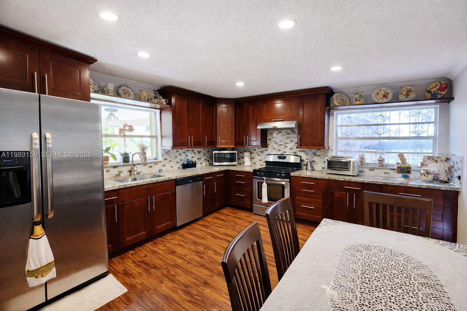 A kitchen features dark wood cabinets, stainless steel appliances, and a dining table — 7344 SW 135th Ct, Miami FL 33183, MIAMI, FL