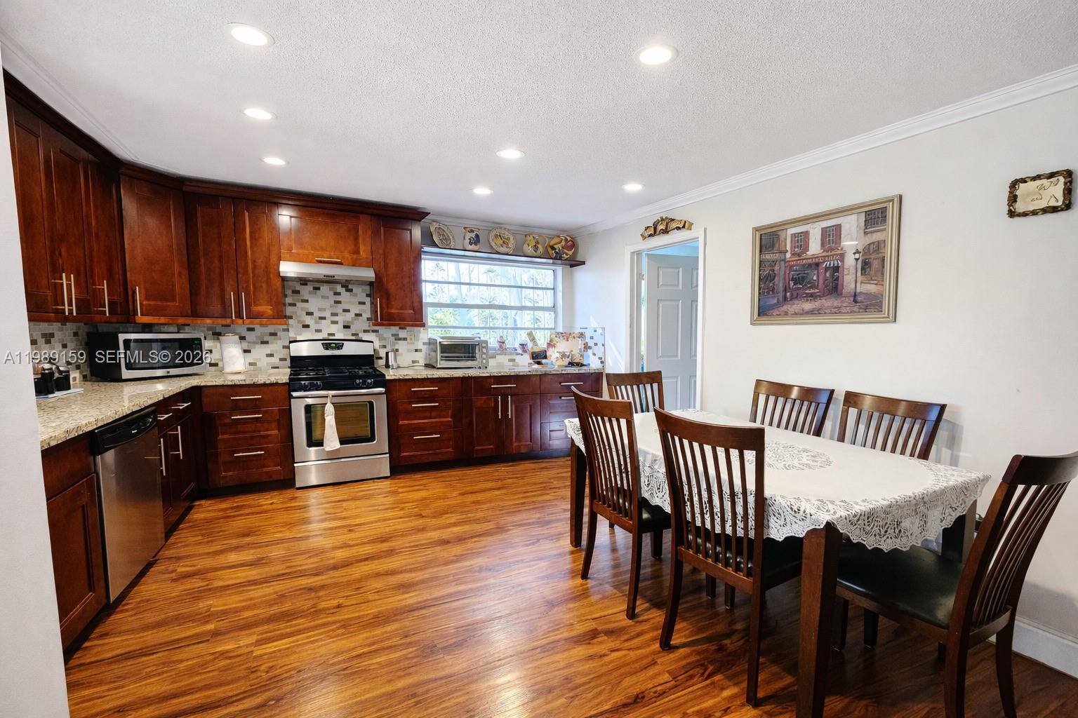 A kitchen with dark wood cabinets, stainless steel appliances, and an adjacent dining area — 7344 SW 135th Ct, Miami FL 33183, MIAMI, FL