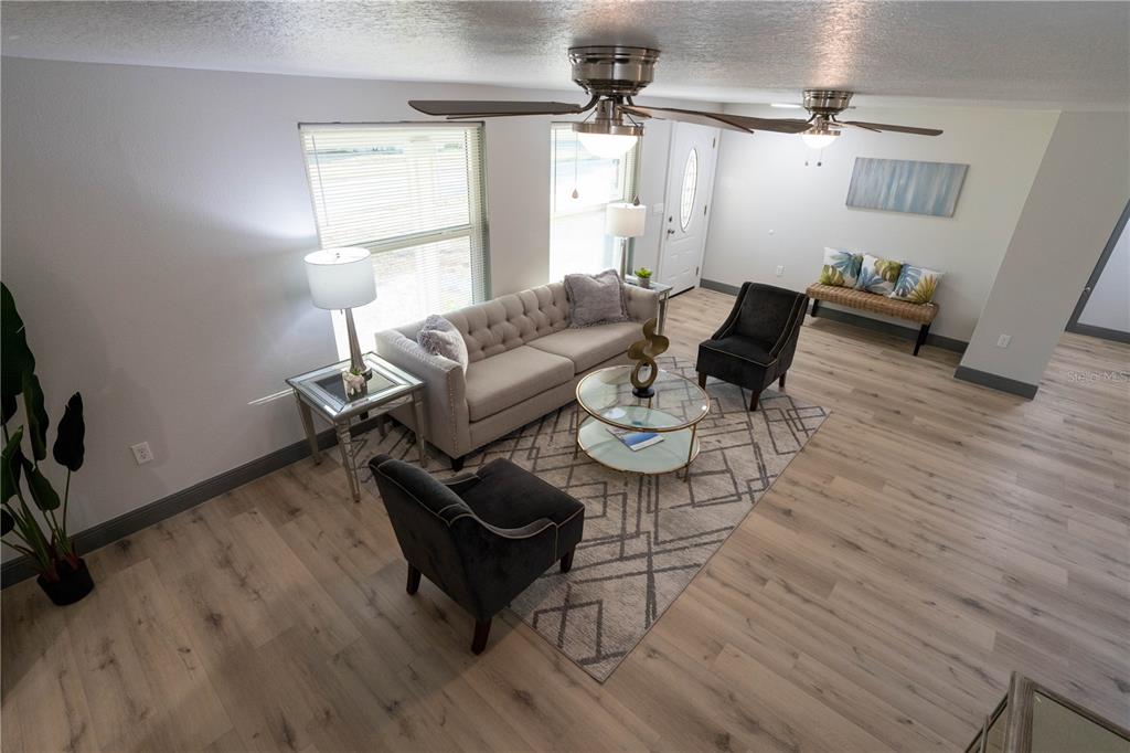 A living room features a tufted sofa, two armchairs, a glass coffee table, and wood flooring — 2908 EDENWOOD STREET, CLEARWATER, FL
