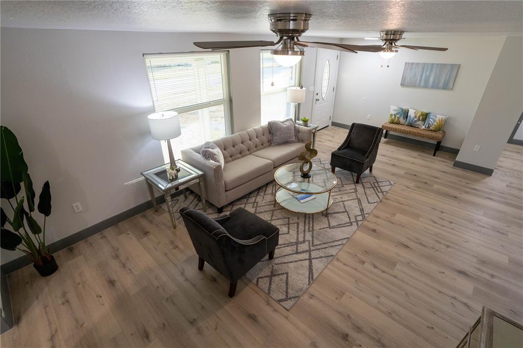 A living room features a tufted sofa, two dark armchairs, and light wood flooring — 2908 EDENWOOD STREET, CLEARWATER, FL