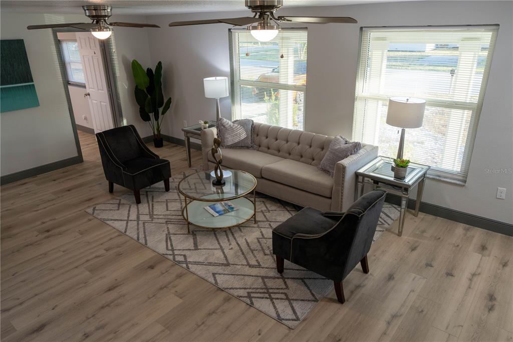 A living room features a tufted sofa, two armchairs, a glass coffee table, and wood flooring — 2908 EDENWOOD STREET, CLEARWATER, FL