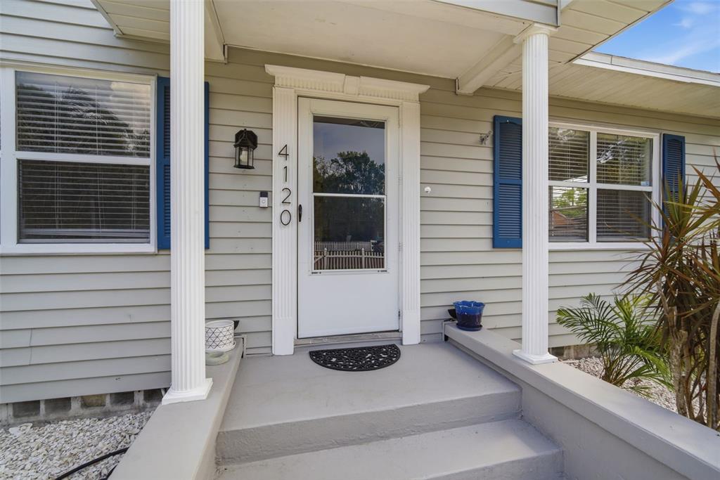 The exterior of a house features a white front door, gray siding, and two columns — 4120 BURLINGTON AVENUE N, ST PETERSBURG, FL