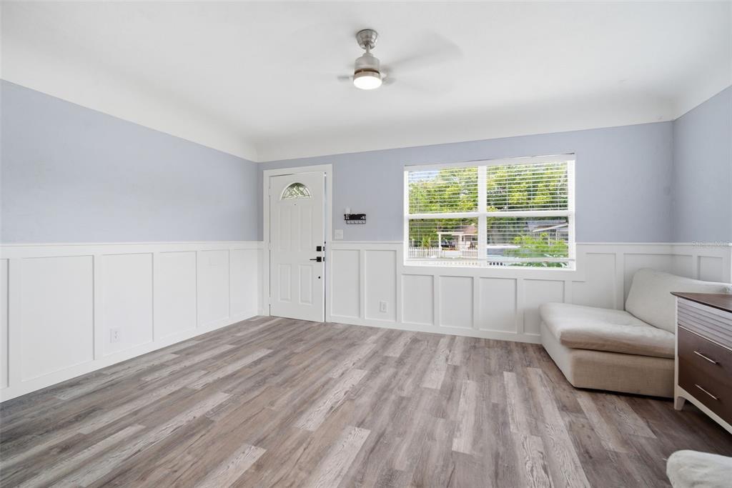 A room with light blue walls, white wainscoting, wood-look flooring, and a ceiling fan — 4120 BURLINGTON AVENUE N, ST PETERSBURG, FL