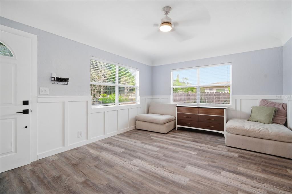A living room features light gray walls, white wainscoting, wood-look flooring, and a ceiling fan — 4120 BURLINGTON AVENUE N, ST PETERSBURG, FL