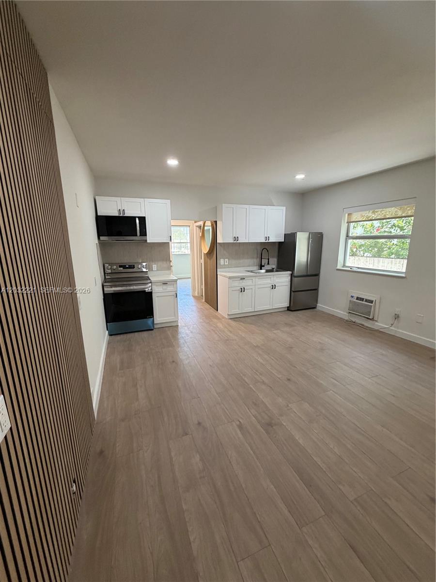 A kitchen features white cabinetry, stainless steel appliances, and light wood-look flooring — 7734 Abbott Ave # 101, Miami Beach FL 33141, MIAMI BEACH, FL