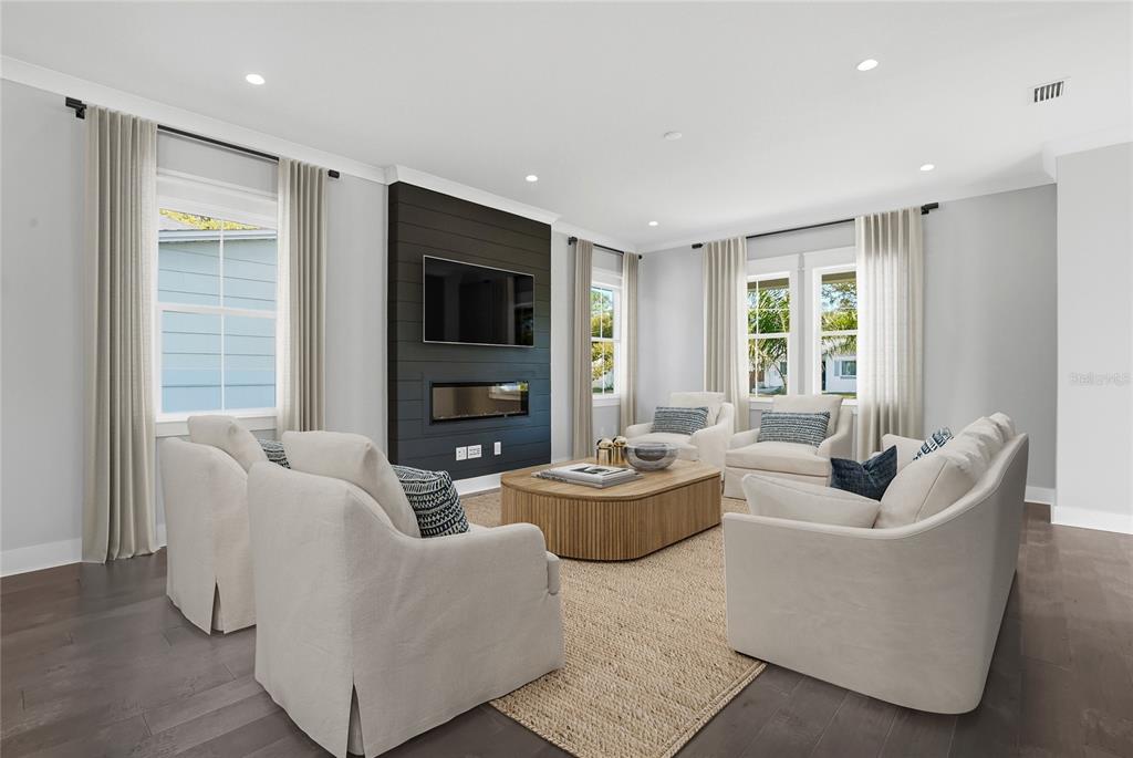 A living room features a dark shiplap fireplace, neutral sofas, and two olive green armchairs — 865 53RD AVENUE N, ST PETERSBURG, FL