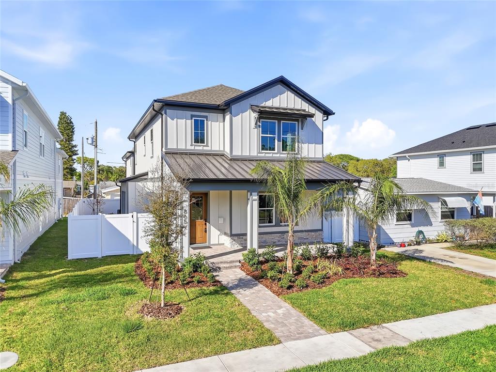 A modern kitchen features a large island with bar stools, white cabinetry, and wood accents — 865 53RD AVENUE N, ST PETERSBURG, FL