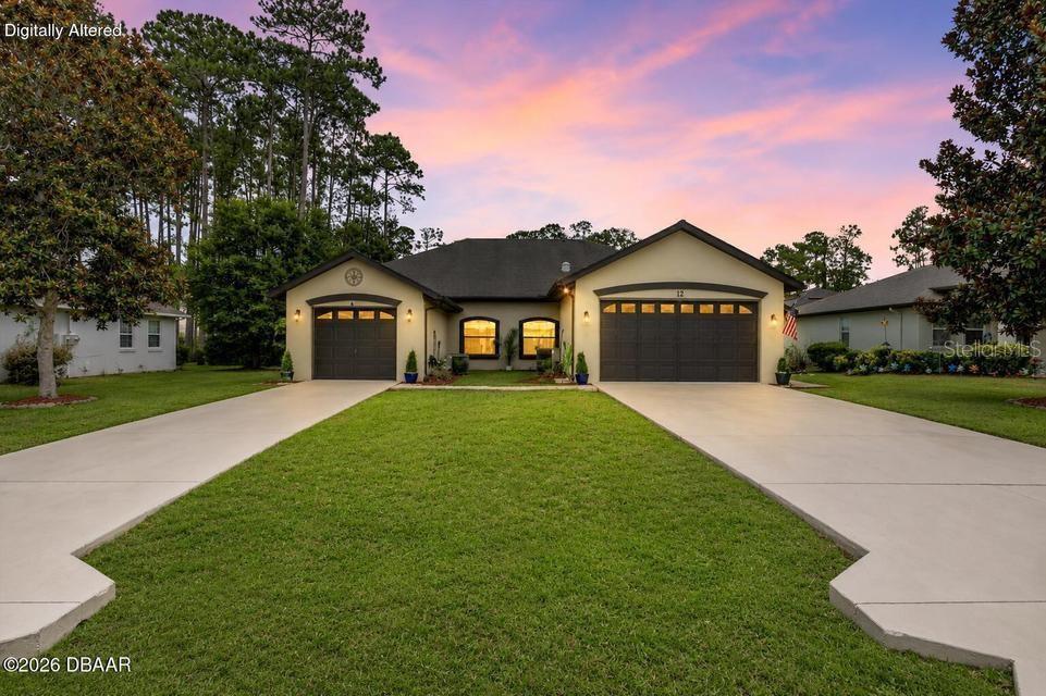 A single-story house with two garage doors and a concrete driveway at sunset — 12 EMMONS LANE, PALM COAST, FL