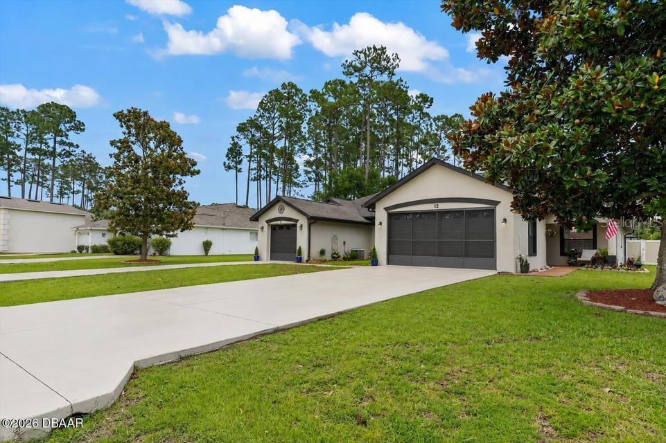 A single-story house with a two-car garage and a large concrete driveway — 12 EMMONS LANE, PALM COAST, FL