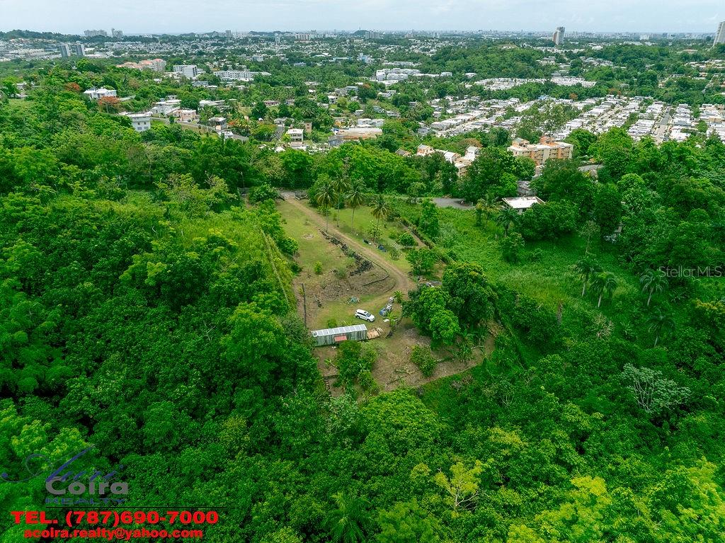 An aerial view shows a cleared rectangular lot surrounded by dense green forest and residential neighborhoods — Lot 6 CAMINO PACO GALÁN, GUAYNABO, PR