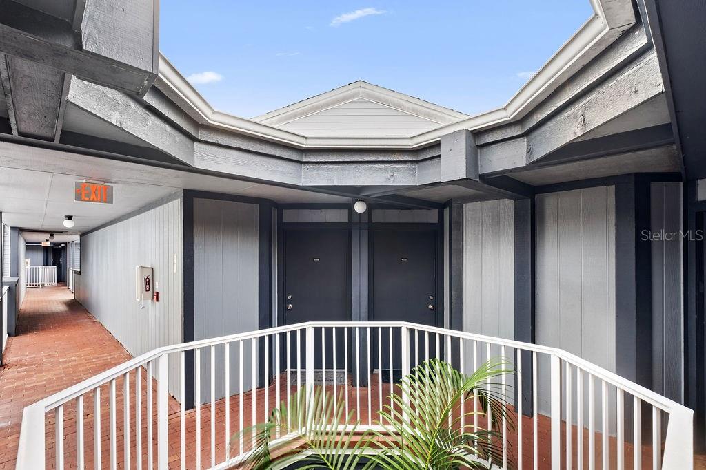 An outdoor walkway leads to two dark-colored apartment doors under a partially open roof — 3998 ATRIUM DRIVE UNIT U-1, ORLANDO, FL