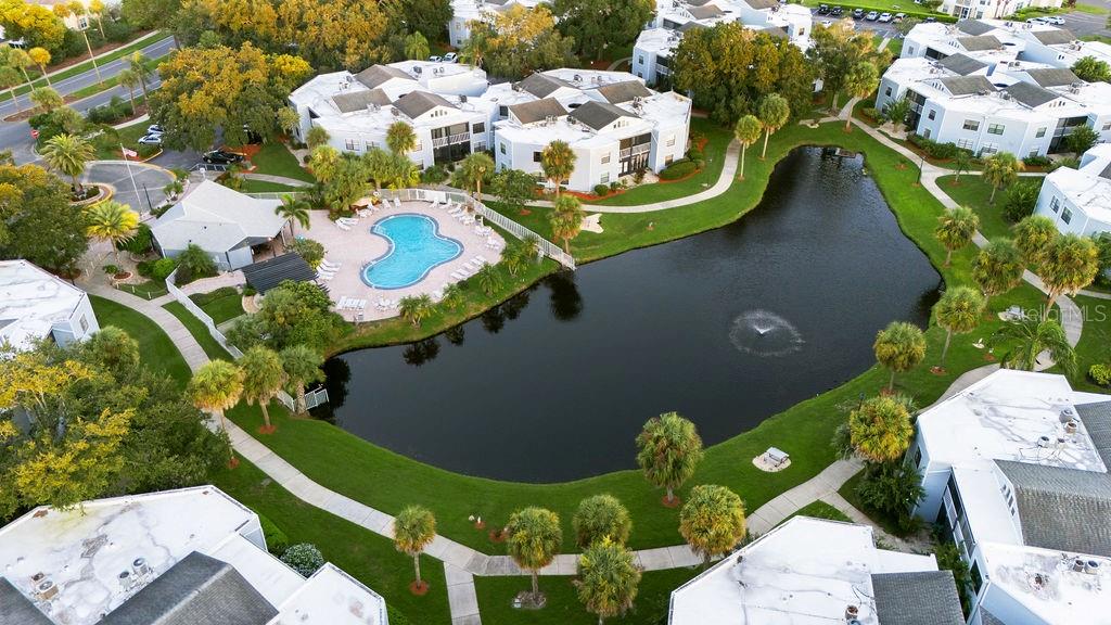 An aerial view shows a residential complex with a central pond, pool, and palm trees — 3998 ATRIUM DRIVE UNIT U-1, ORLANDO, FL